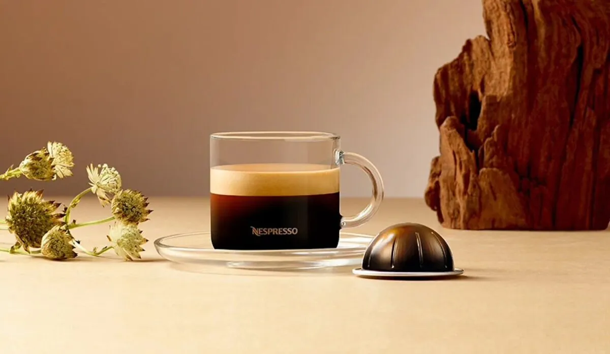 Чашка кофе Nespresso на столе с капсулой.