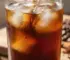Стакан холодного кофе cold brew с кубиками льда на деревянном столе